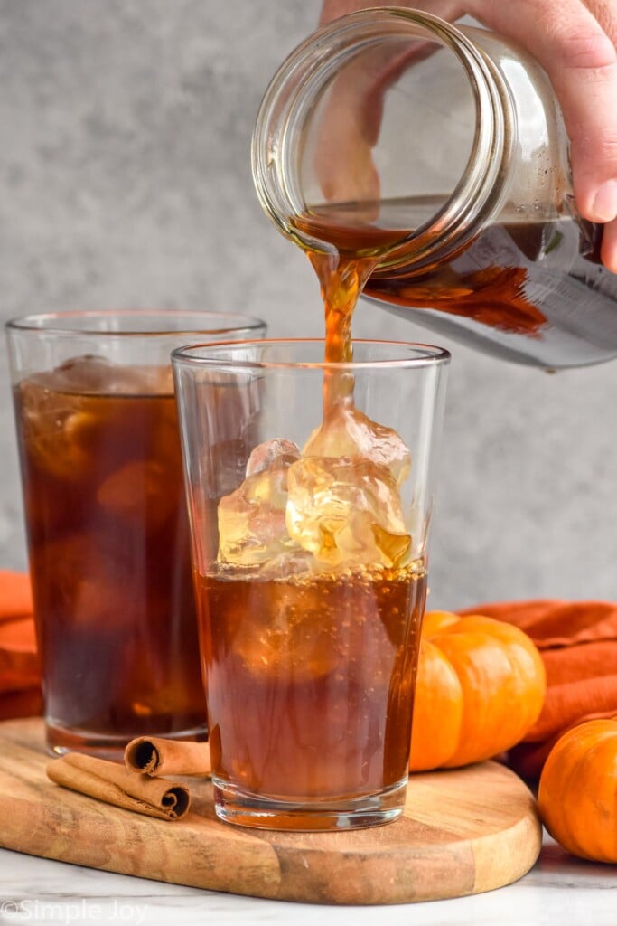 Side view of person's hand pouring jar of cold brew coffee into ice for Pumpkin Cream Cold Brew recipe.