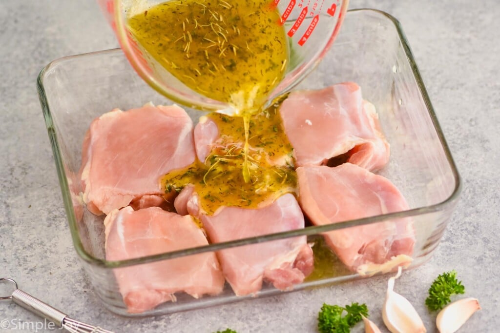 Photo of marinade being poured over chicken thighs in baking dish for Baked Chicken Thighs recipe.