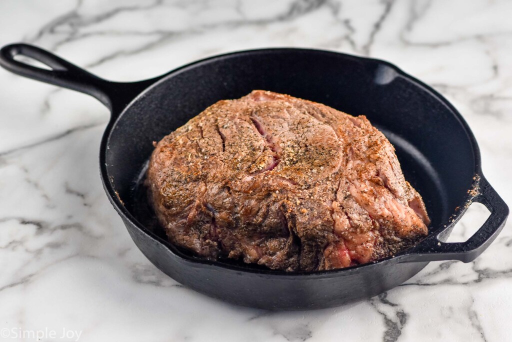 Photo of a cast iron skillet with a roast for Slow Cooker Pot Roast recipe.
