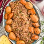 Overhead photo of a platter of Slow Cooker Pot Roast with potatoes. Wine and toast beside. - 12