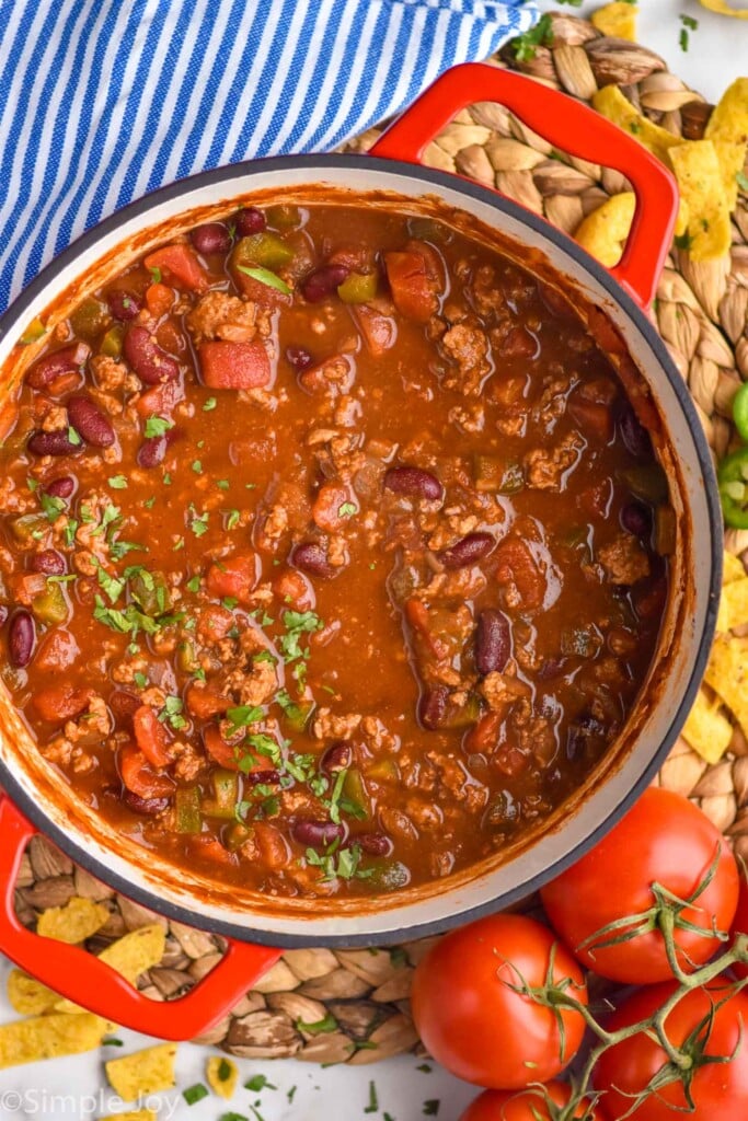 Overhead photo of a pot of Turkey Chili. Tomatoes beside.