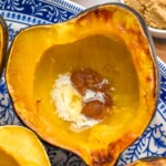Roasted Acorn Squash on a plate. Bowl of brown sugar sitting beside