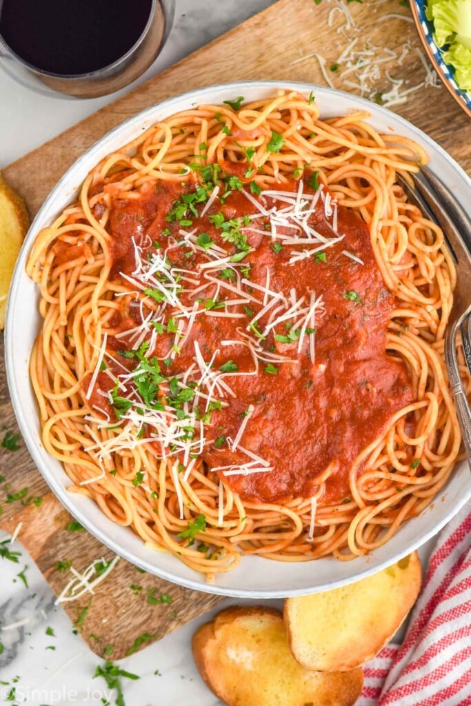 Overhead photo of a plate of pasta with Marinara Sauce. Bread and wine beside.