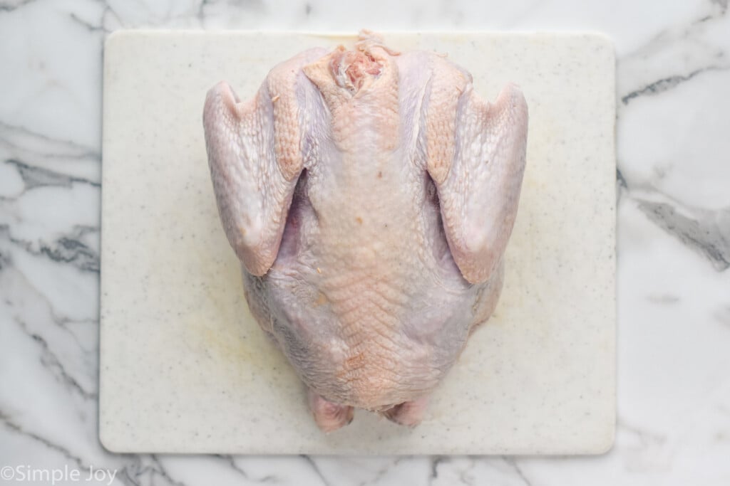 Overhead photo of a raw turkey on a cutting board for Spatchcock Turkey recipe