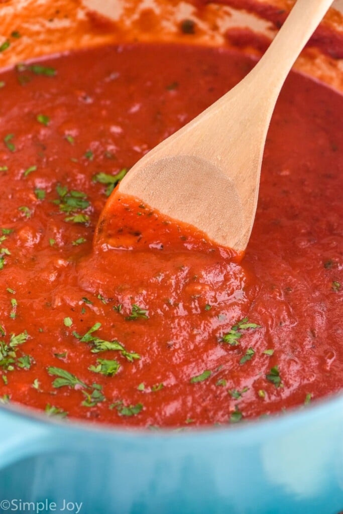 Photo of a pot of Marinara Sauce with a wooden spoon