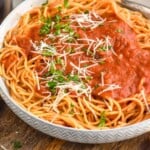 Pinterest graphic for Marinara Sauce recipe. Image shows a bowl of pasta with Marinara Sauce. Wine and salad beside. Text says, "super easy Marinara Sauce simplejoy.com"