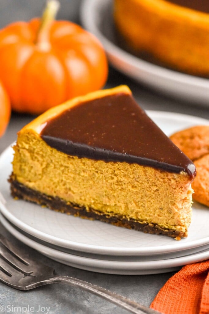 Slice of Pumpkin Cheesecake served on a plate. Fork and pumpkin beside.