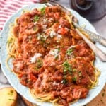 plate of Chicken Cacciatore with a fork for serving. Glasses of red wine and bowl of salad sitting beside. - 10