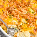 Photo of a baking dish of Scalloped Potatoes with a spoon for serving.