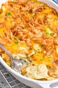 Photo of a baking dish of Scalloped Potatoes with a spoon for serving.