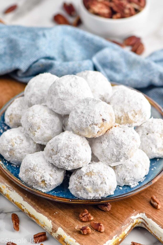 plate of Snowball cookies with pecans surrounding.