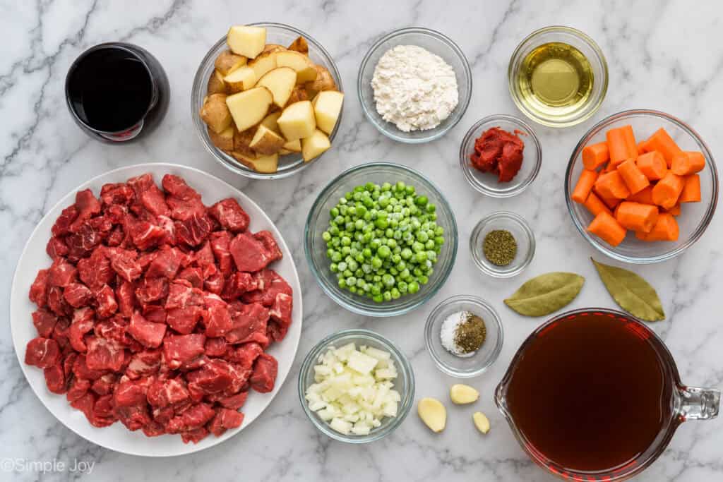 overhead of all the ingredients for beef stew in bowls