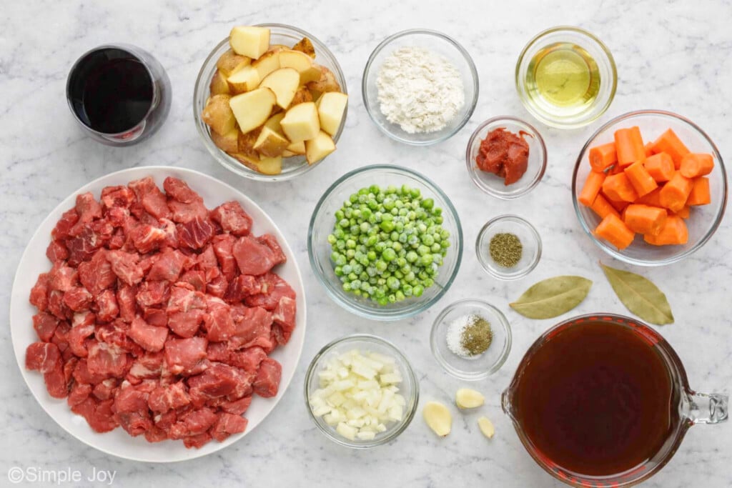 overhead of all the ingredients for beef stew in bowls