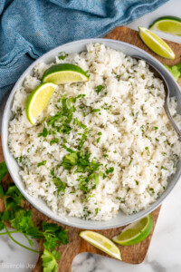 overhead of a bowl of cilantro lime rice garnished with two lime wedges and extra cilantro
