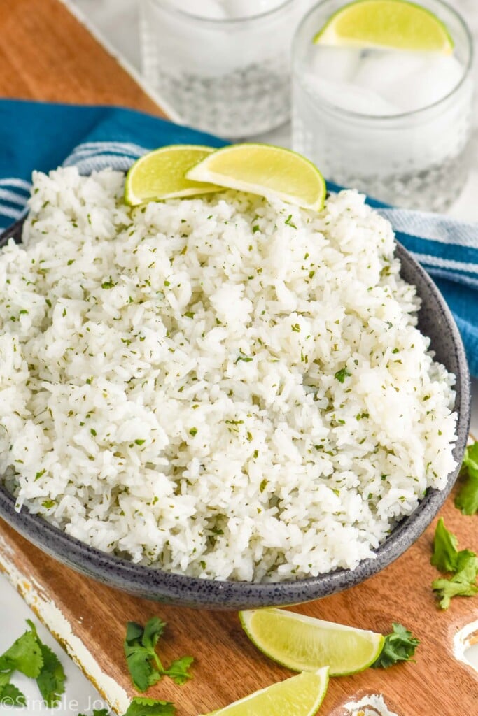 Bowl of Cilantro Lime Rice with margaritas, lime wedges, and cilantro beside