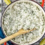 Overhead photo of a pot of Cilantro Lime Rice on a cooling rack with a spoon. Lime wedges and cilantro beside. - 8