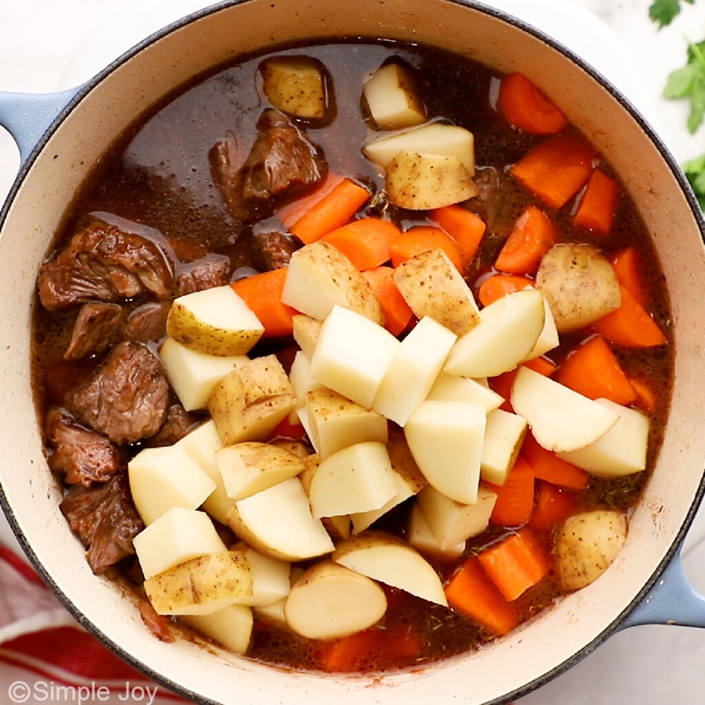 carrots and potatoes added to a dutch oven to make beef stew