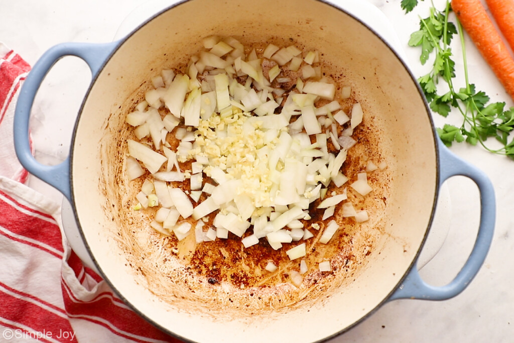 overhead of a dutch oven with onion and garlic to be sautéed