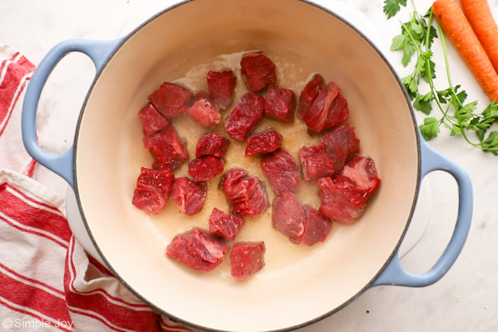 overhead of a dutch oven searing pieces of chuck roast for beef stew