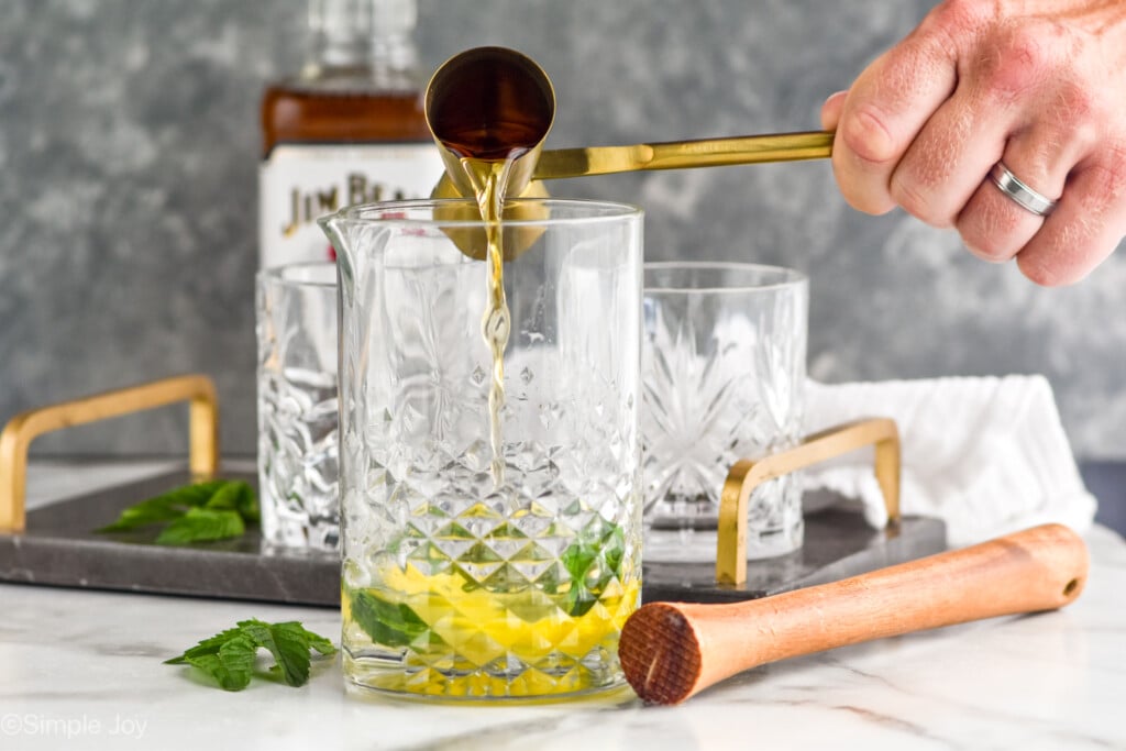 whiskey being poured into a mixing glass