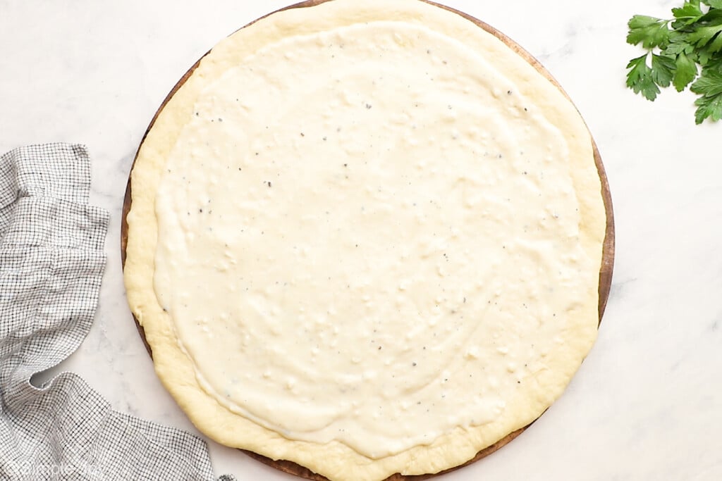 white pizza sauce on pizza dough