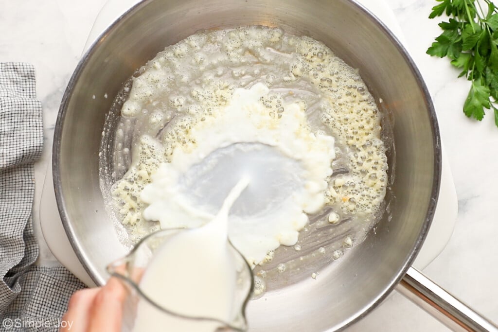 adding heavy cream to a skillet that has butter and garlic to create a cream sauce