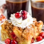 Pinterest graphic for Cranberry French Toast Casserole recipe. Text says, "amazing Cranberry French Toast Casserole simplejoy.com." Image shows Cranberry French Toast Casserole on a plate garnished with whipped cream and cranberries. Cups of coffee beside.