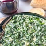 Pinterest graphic for Creamed Spinach recipe. Text says, "the best Creamed Spinach simplejoy.com." Image shows a bowl of Creamed Spinach with bread and wine beside.
