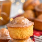 Pinterest graphic for Eggnog Muffins recipe. Text says, "delicious Eggnog Muffins simplejoy.com." Image is side view of a stack of two Eggnog Muffins with cinnamon sticks beside.