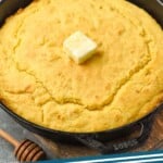 Pinterest graphic for Skillet Cornbread recipe. Image shows Skillet Cornbread with butter and honey beside. Text says, "Skillet Cornbread simplejoy.com"