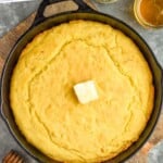 Pinterest graphic for Skillet Cornbread recipe. Text says, "the best Skillet Cornbread simplejoy.com." Image is overhead photo of Skillet Cornbread with butter and honey beside.