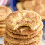 Pinterest graphic for Snickerdoodles recipe. Text says, "Snickerdoodle Cookies simplejoy.com." Image shows a stack of Snickerdoodles with a bite taken out of the top cookie. Cinnamon sticks beside.