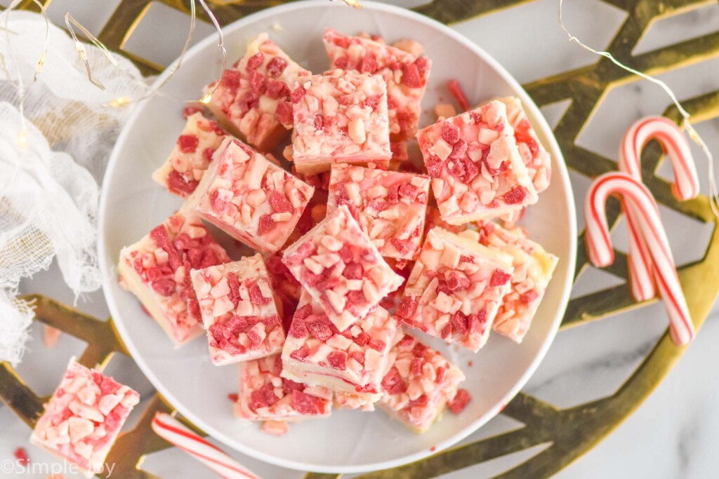 overhead image of plate of peppermint fudge with candy canes sitting beside.