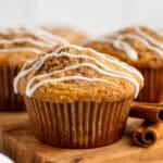 a coffee cake muffin on a cutting board with two cinnamon sticks
