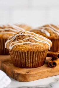 a coffee cake muffin on a cutting board with two cinnamon sticks