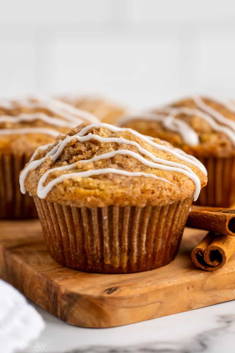 a coffee cake muffin on a cutting board with two cinnamon sticks