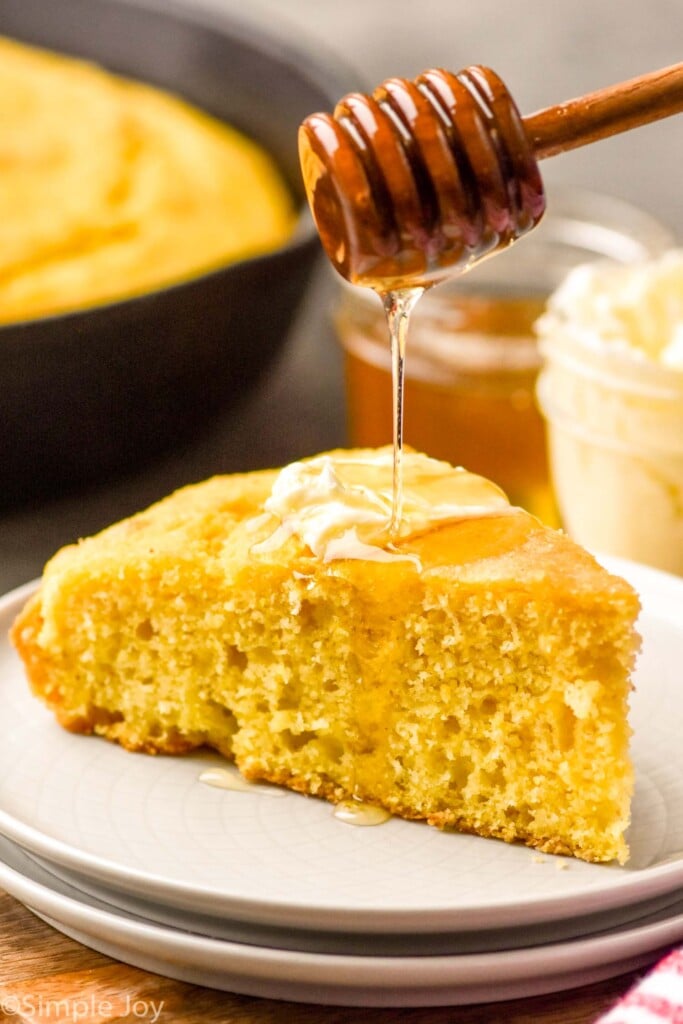 Side view of honey being drizzled over a slice of Skillet Cornbread on a plate.