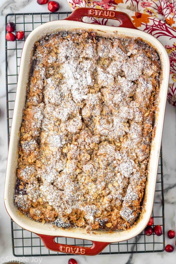 Overhead photo of a baking dish of Cranberry French Toast Casserole on a cooling rack. Cranberries beside.