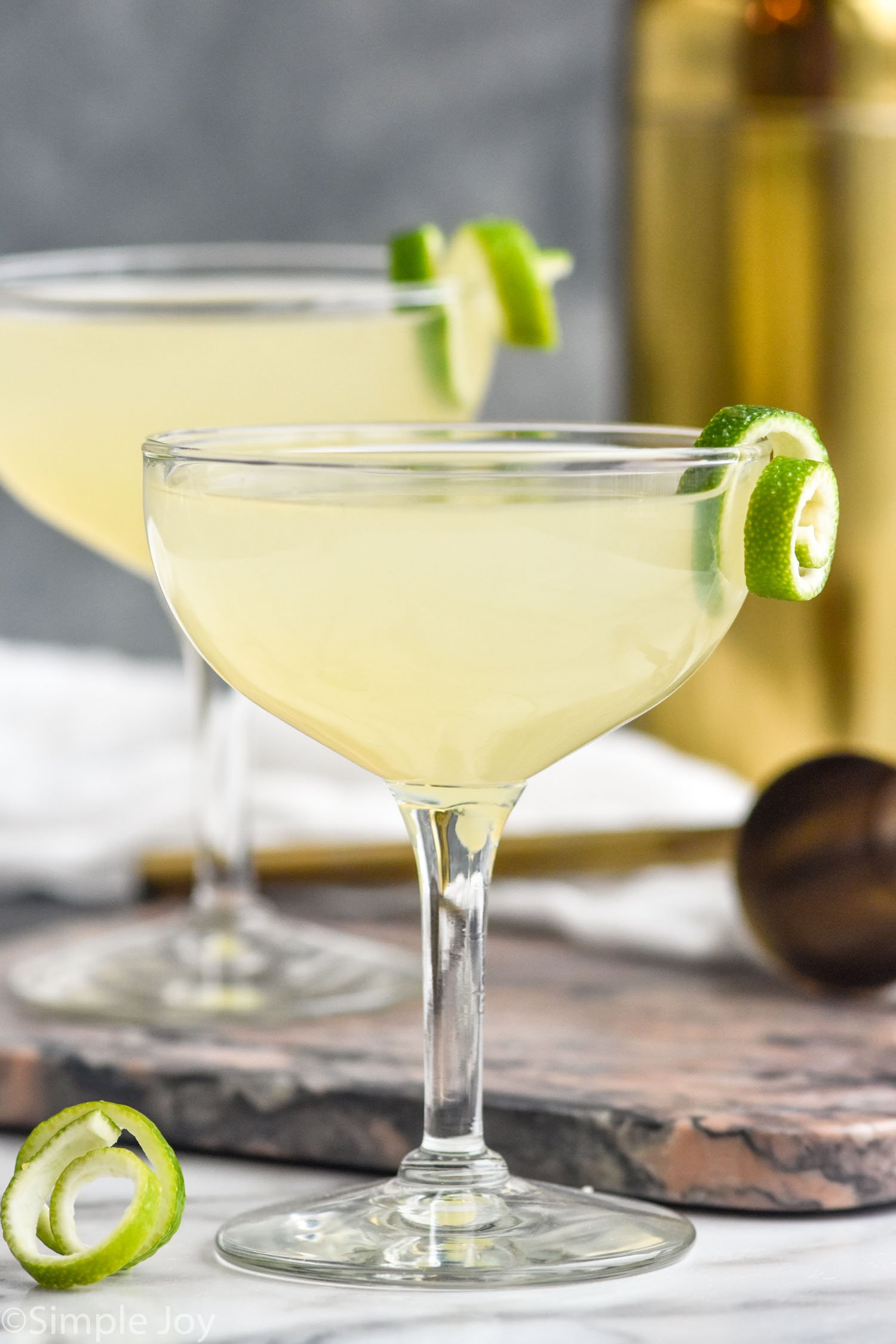 two glasses of daiquiri cocktails garnished with a lime twist