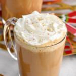 Photo of mugs of Eggnog Latte garnished with whipped cream with cinnamon sticks beside.