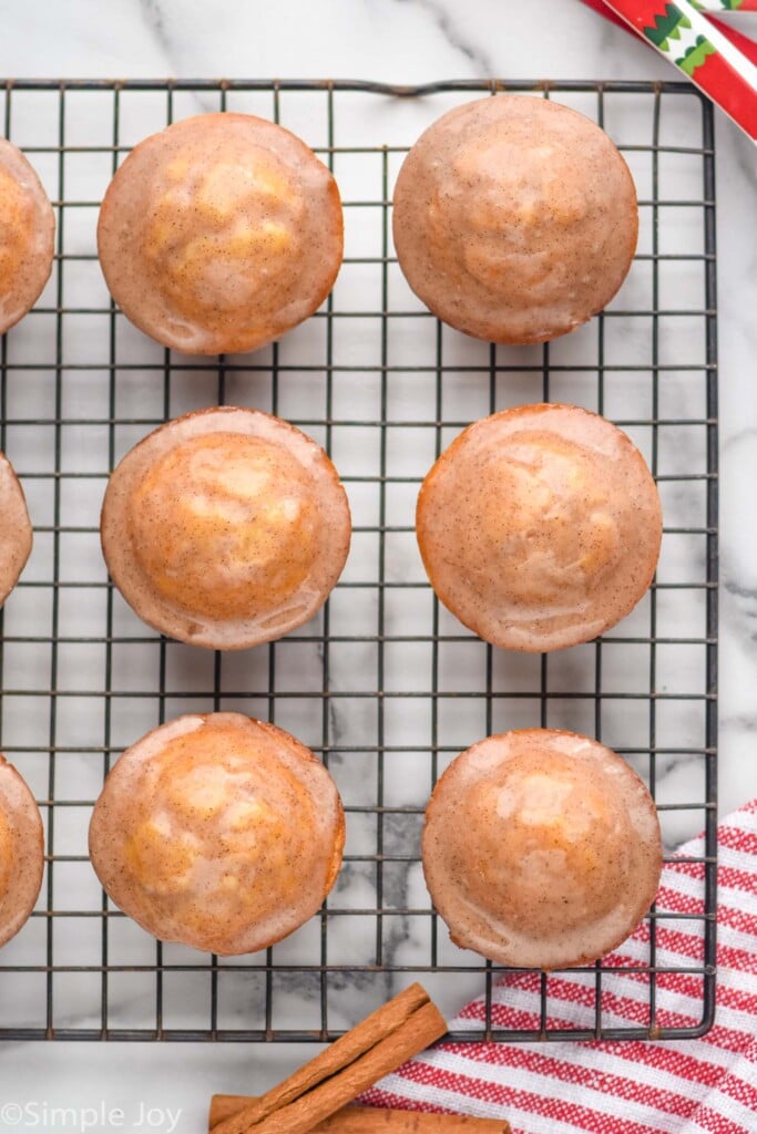 Overhead view of Eggnog Muffins on cooling rack with cinnamon sticks beside