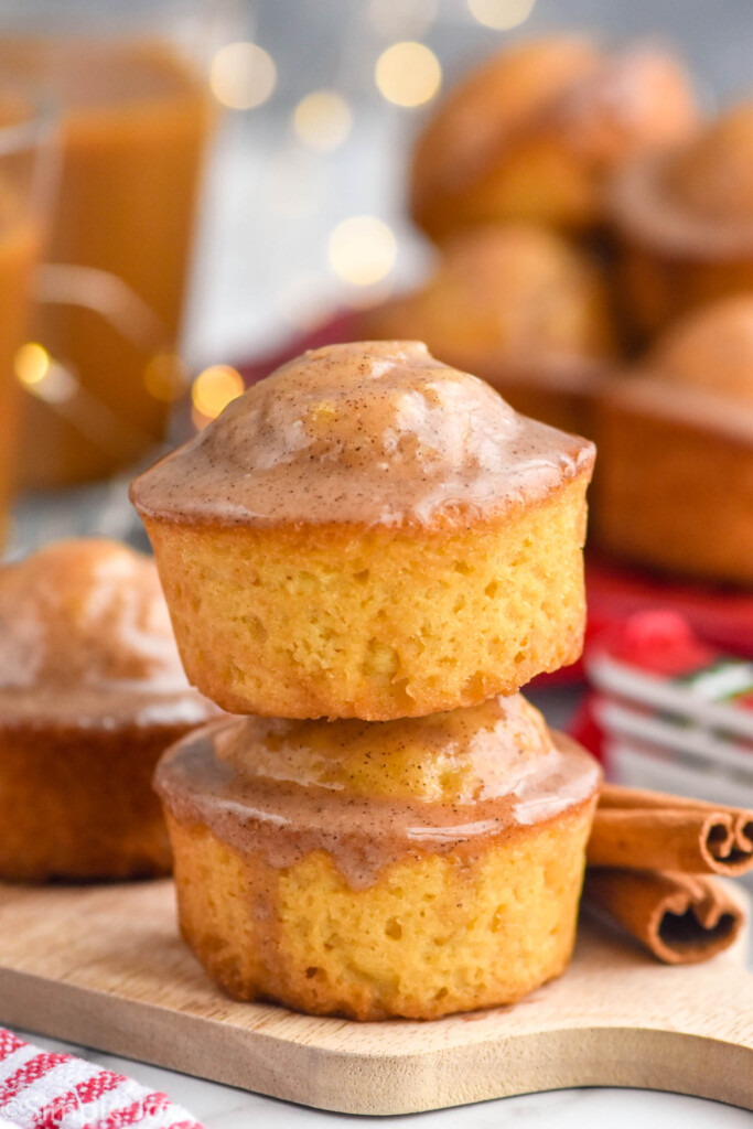 Side view of a stack of two Eggnog Muffins with cinnamon sticks beside