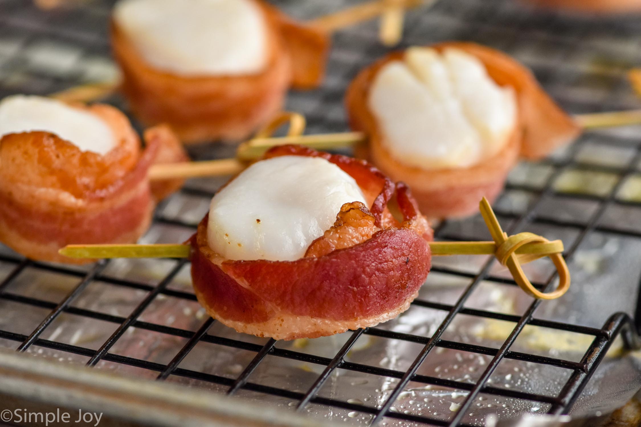 Close up photo of Bacon Wrapped Scallops on a baking sheet