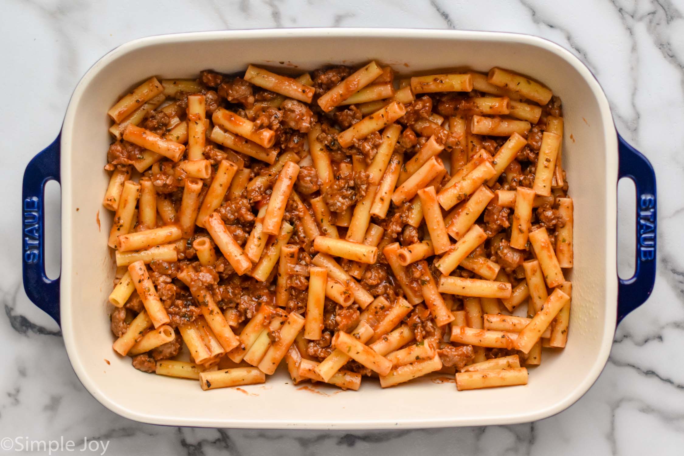 Overhead photo of a baking dish of ingredients for Baked Ziti recipe