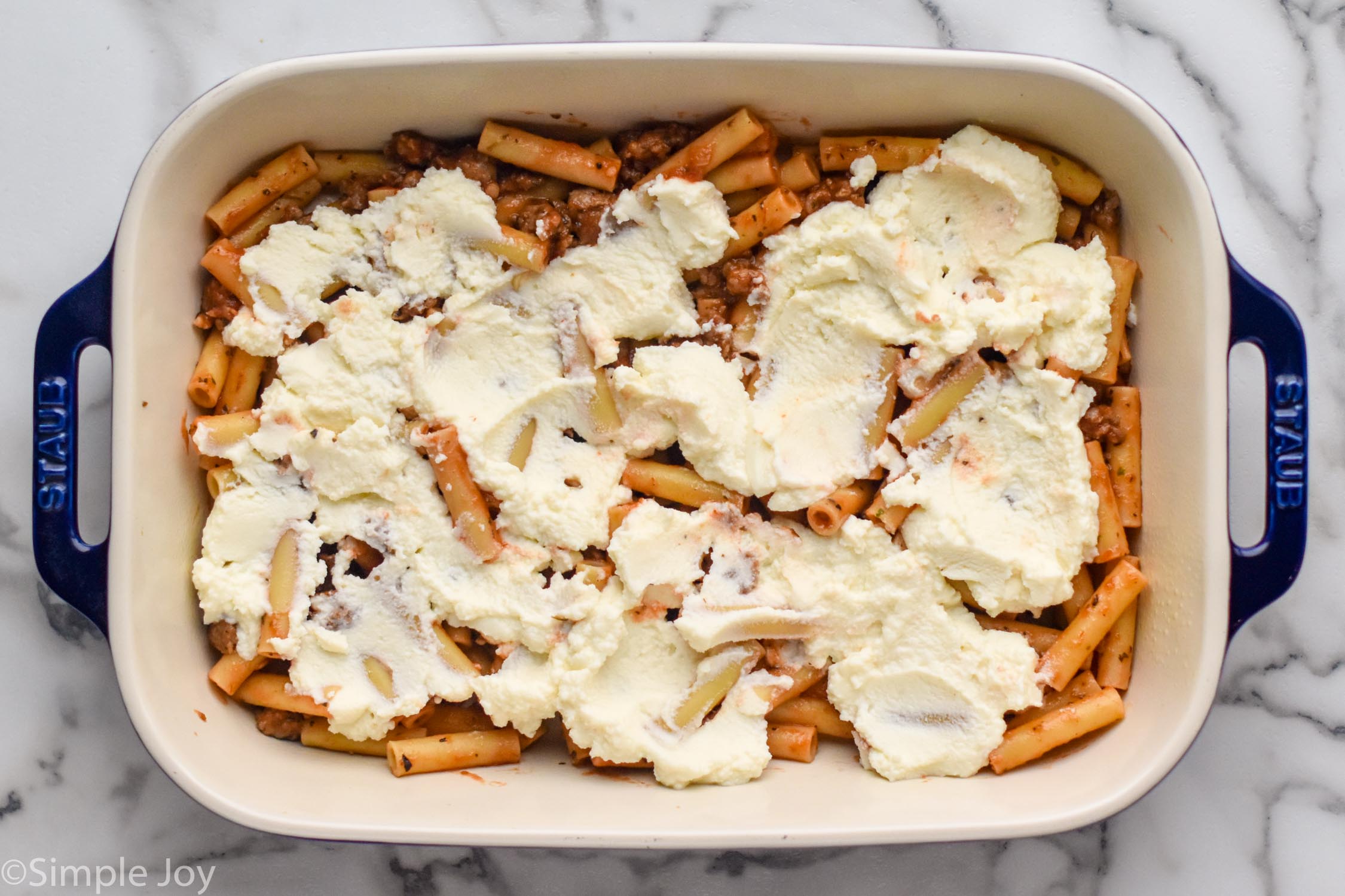 Overhead photo of a baking dish of ingredients for Baked Ziti recipe