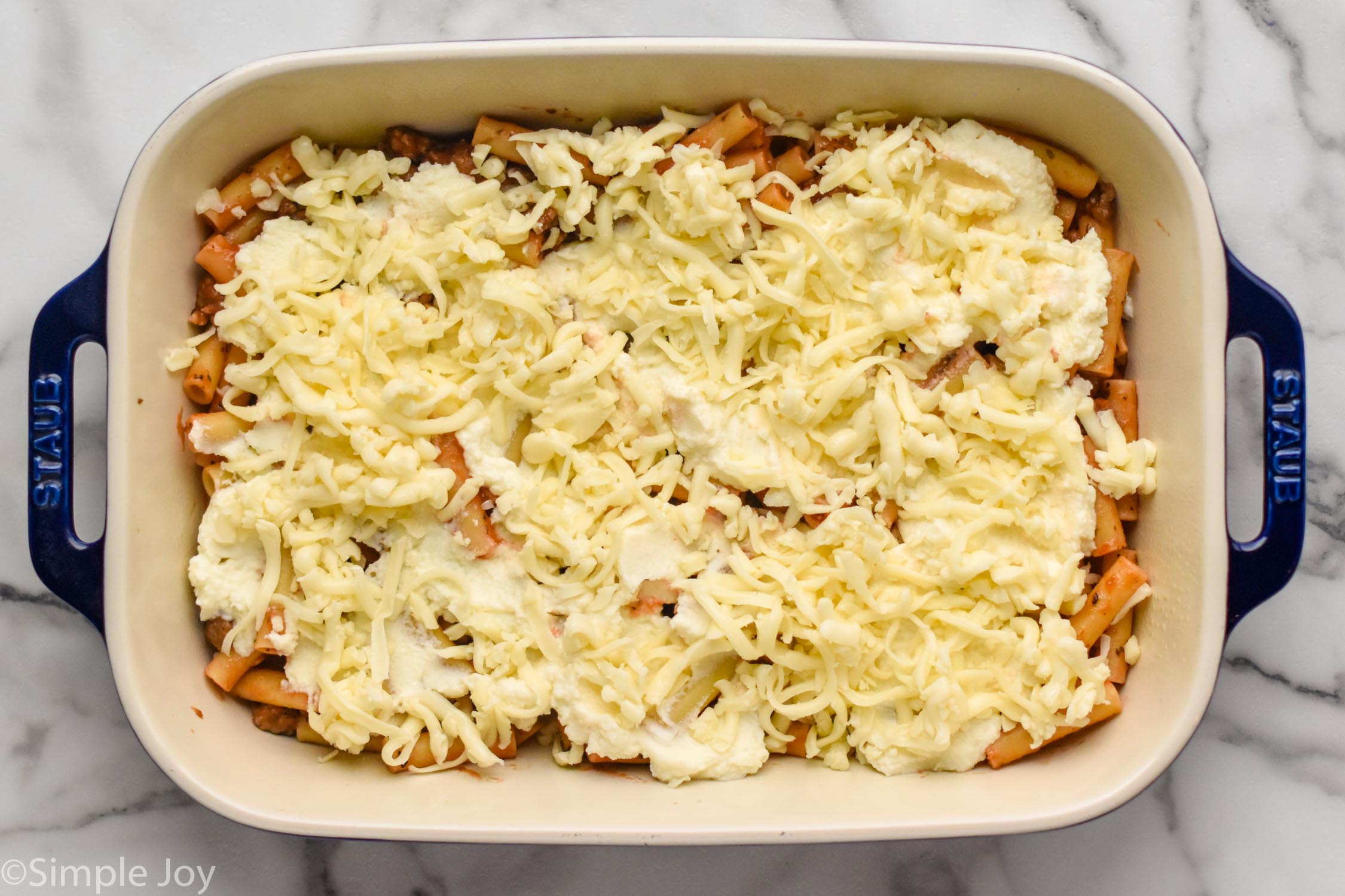 Overhead photo of a baking dish of ingredients for Baked Ziti recipe