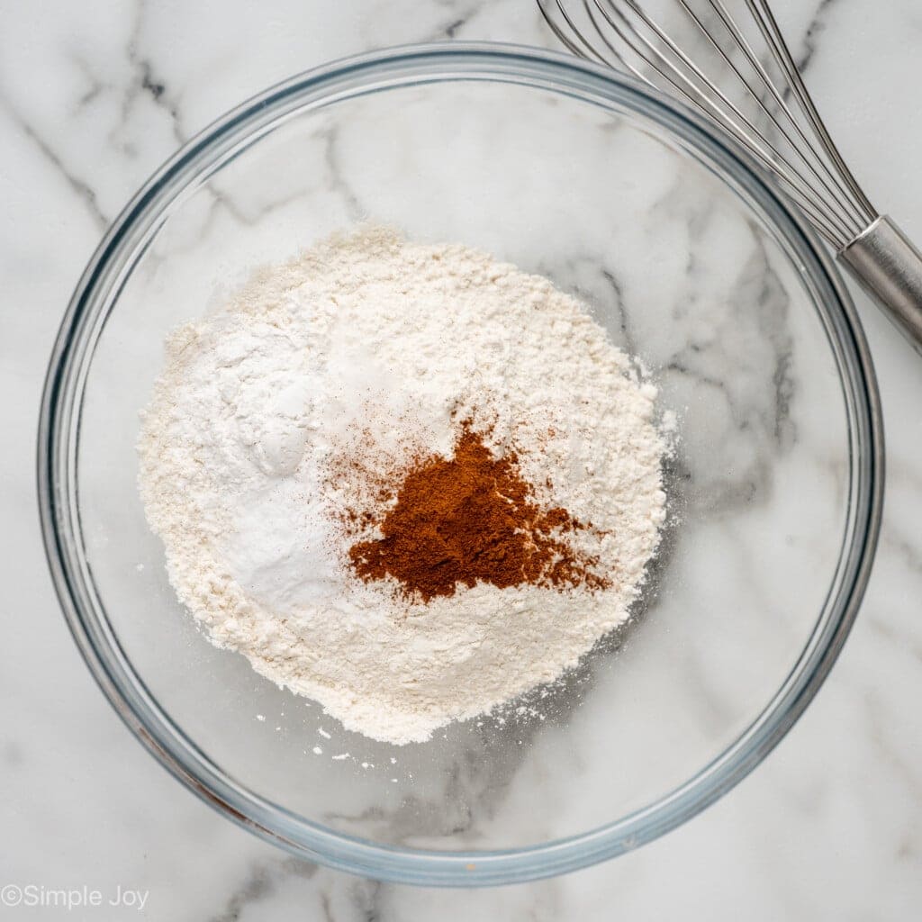 overhead of a bowl of flour, baking powder, baking soda, cinnamon, and salt