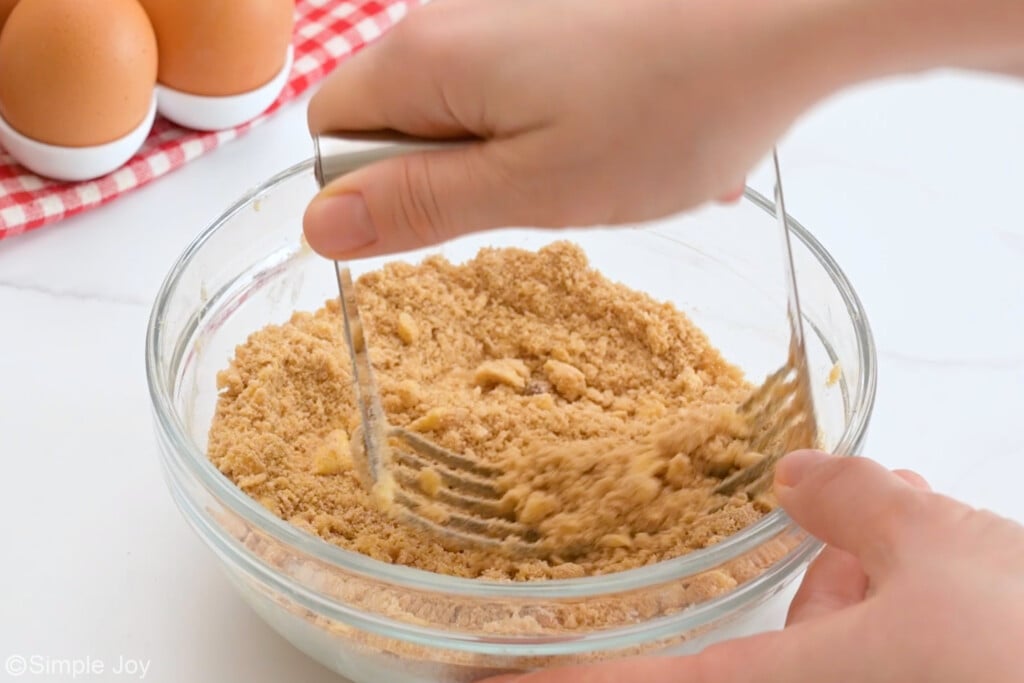 a pastry cutter being pressed into a bowl to make a streusel topping