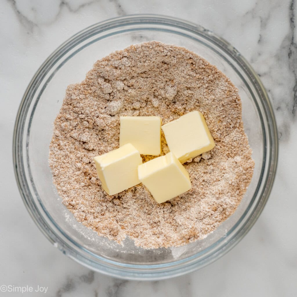 overhead of a bowl of whisked brown sugar, cinnamon, and flour with four pieces of butter
