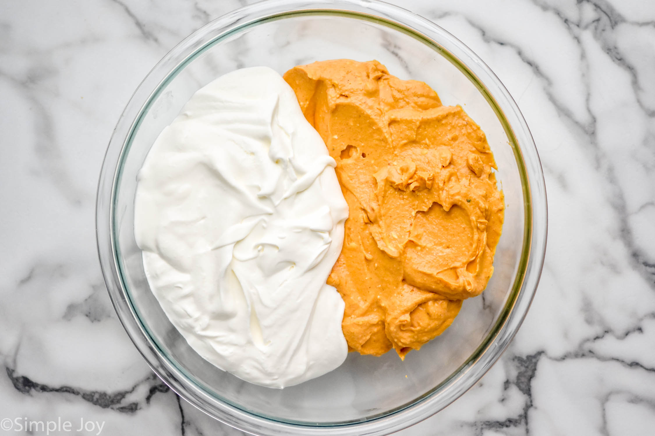 Overhead photo of a mixing bowl of ingredients for No Bake Pumpkin Cheesecake recipe.